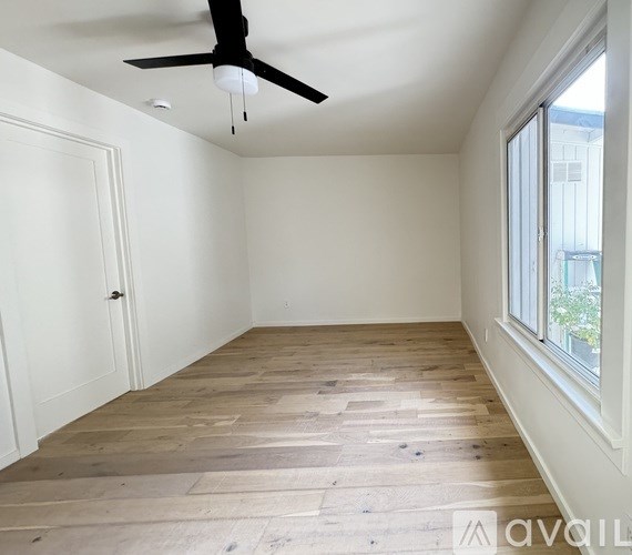A room with wooden flooring and a ceiling fan.
