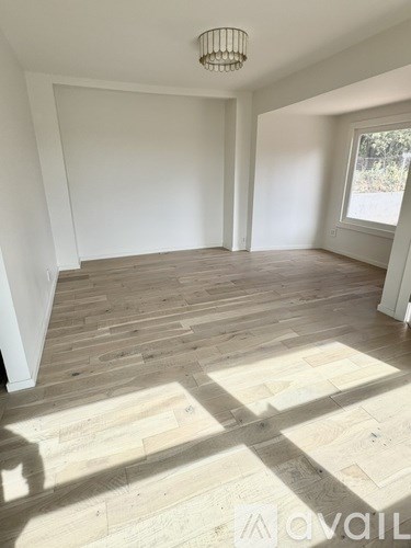 A room with wooden flooring and white walls.