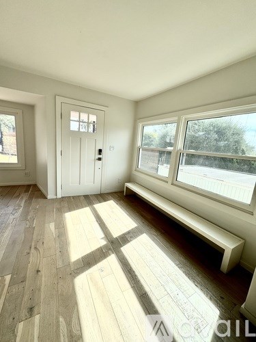 A room with a white door, a window, and a bench.