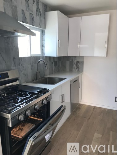 A kitchen with a stove, sink, and cabinets.