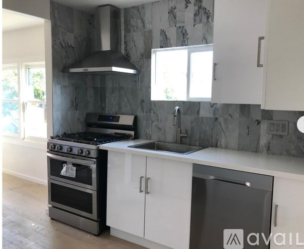 A modern kitchen with a black stove and white cabinets.
