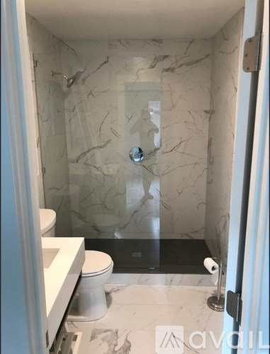 A bathroom with a marble wall and a glass shower door.