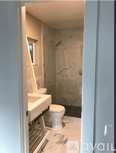 A bathroom with a toilet, sink, and marble tiles.
