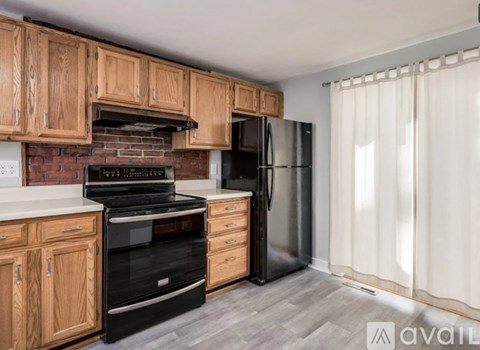 A kitchen with wooden cabinets and a black refrigerator.