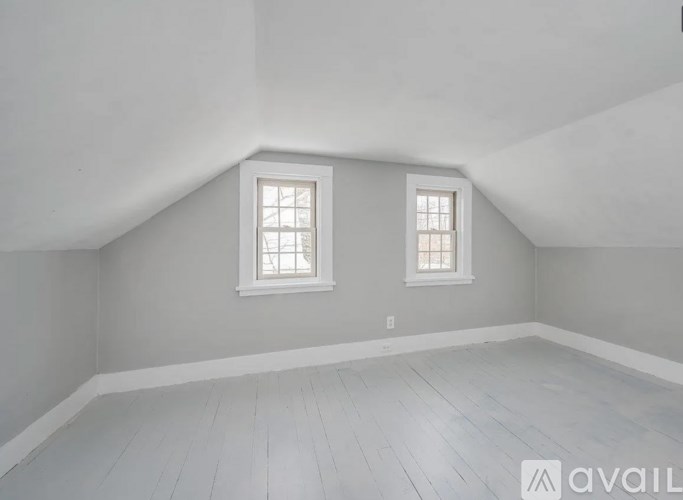 A room with two windows and wooden flooring.
