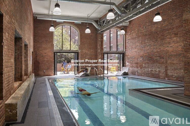 A swimming pool inside a building with a sign that says "Boston Proper Real Estate".