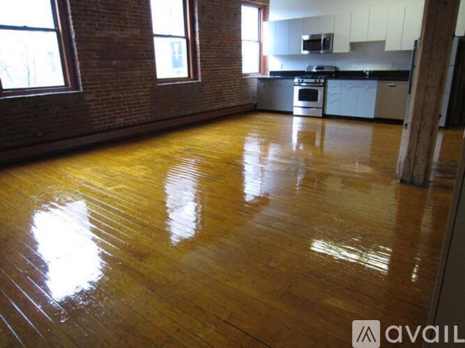 A room with wooden floors and a brick wall.