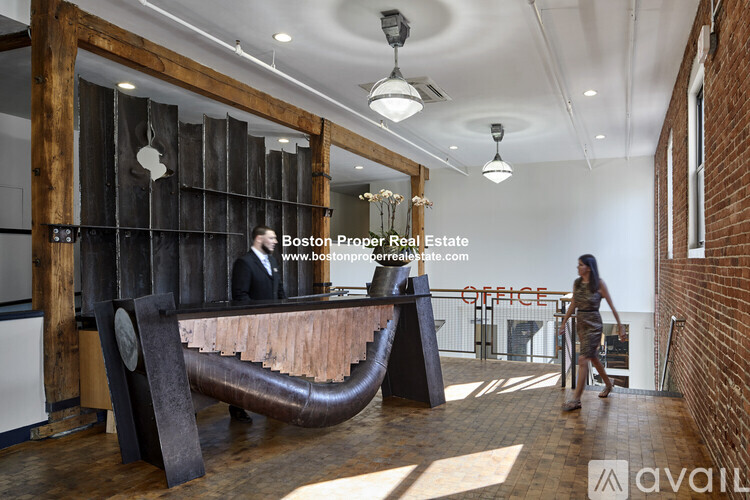 A woman walks through a modern office space with a wooden reception desk.