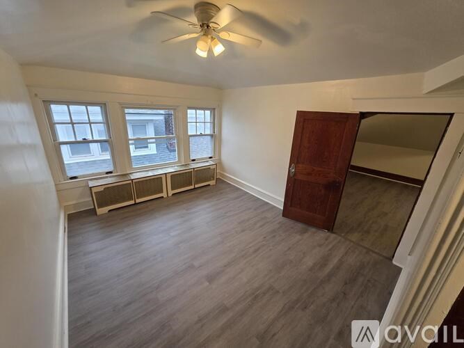 A room with a ceiling fan and three windows.