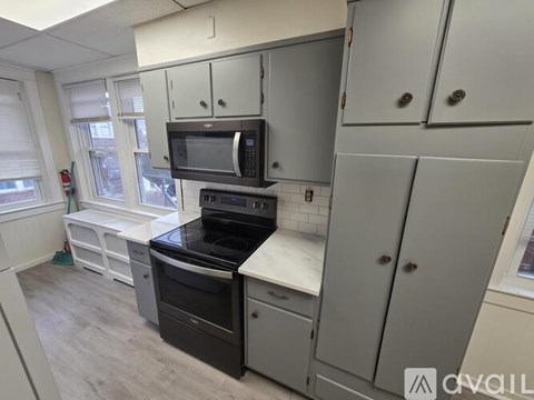 A kitchen with a black stove top oven and a black microwave above it.