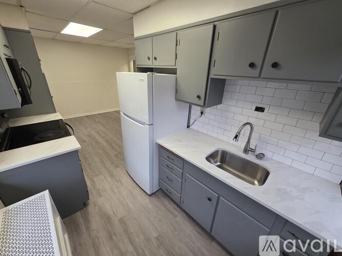 A kitchen with a white fridge, sink, and cabinets.