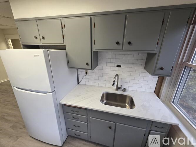 A kitchen with a white fridge and a white sink.