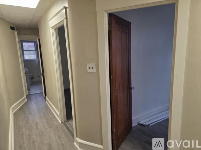 A hallway with a door on the right and a window on the left.