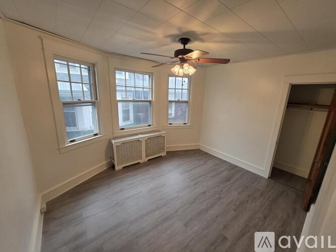 A room with a ceiling fan and two windows.