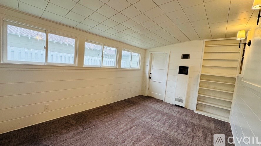 A room with a carpeted floor, a staircase, and a window.