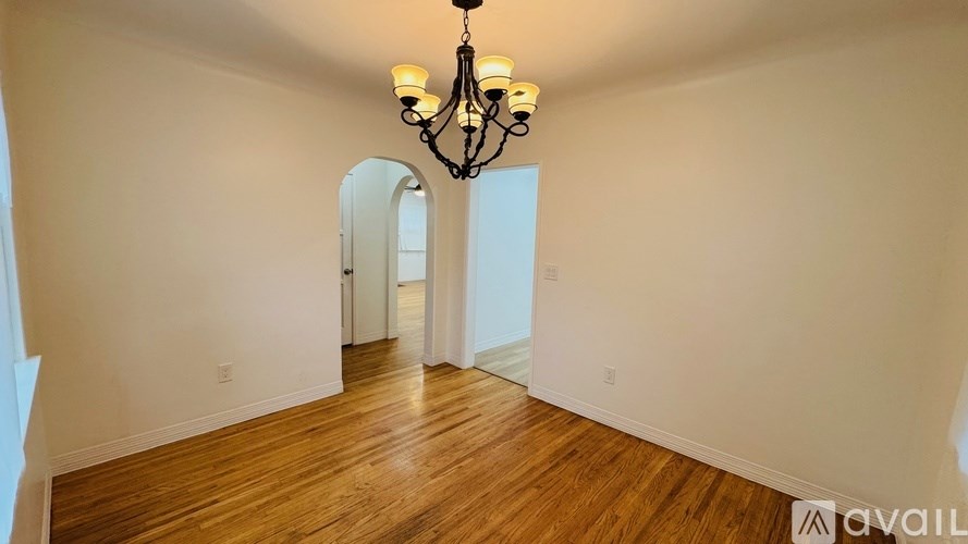 A room with a chandelier and a wooden floor.