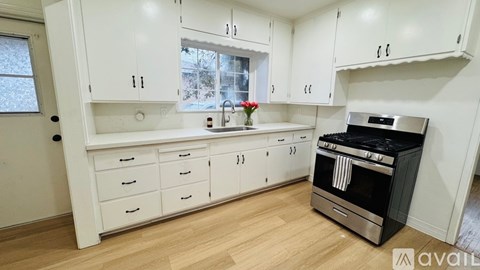 A kitchen with white cabinets and a black stove top oven.