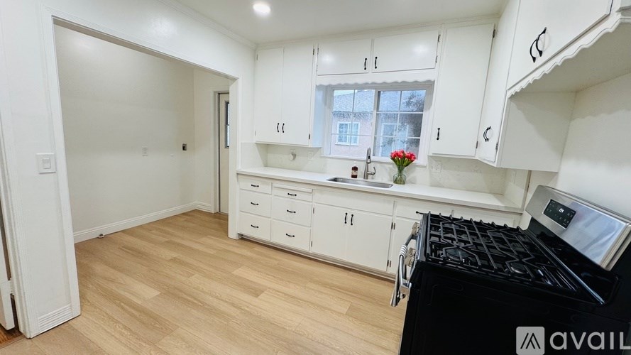 A kitchen with white cabinets and a black stove top oven.