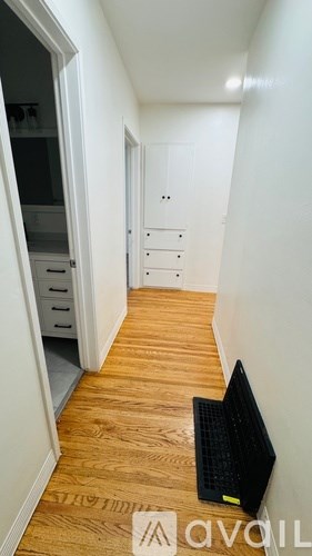 A black laptop is on the floor of a hallway.