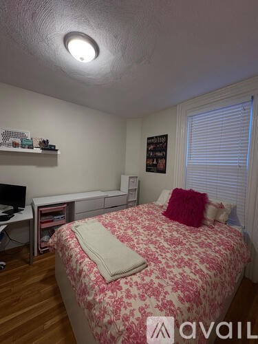 A bedroom with a bed, a desk, and a shelf.
