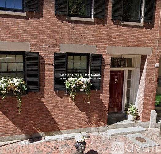 A red brick building with a red door and windows with shutters.