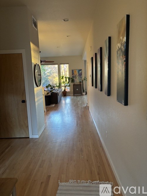 A hallway with wooden floors and a series of paintings on the wall.