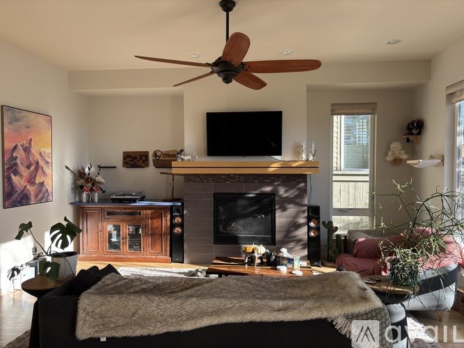 A living room with a fireplace, television, and a ceiling fan.