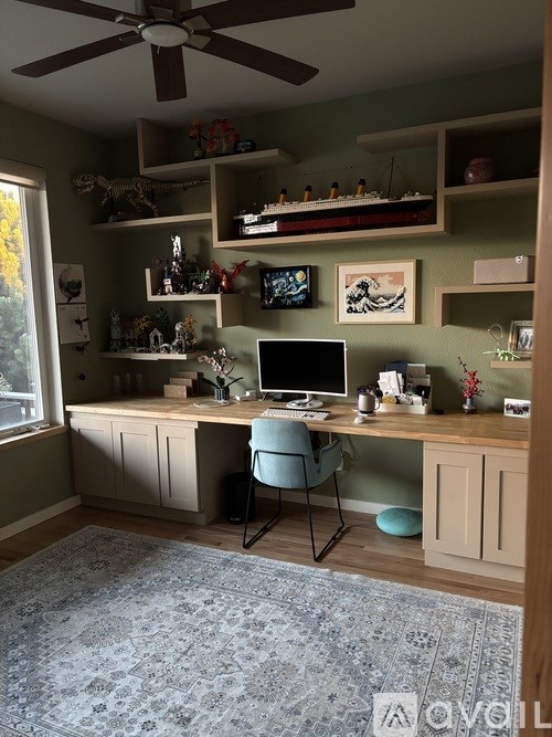 A room with a desk, chair, and shelves with various items.