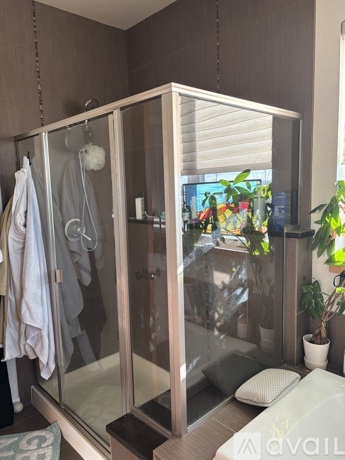 A bathroom with a glass shower stall and a towel hanging on the door.