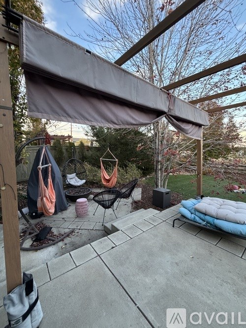 A patio area with a grey awning and a blue cushioned bench.