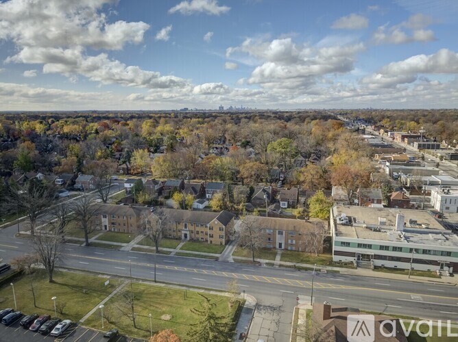 A view of a town with apartment buildings and trees with autumn leaves.