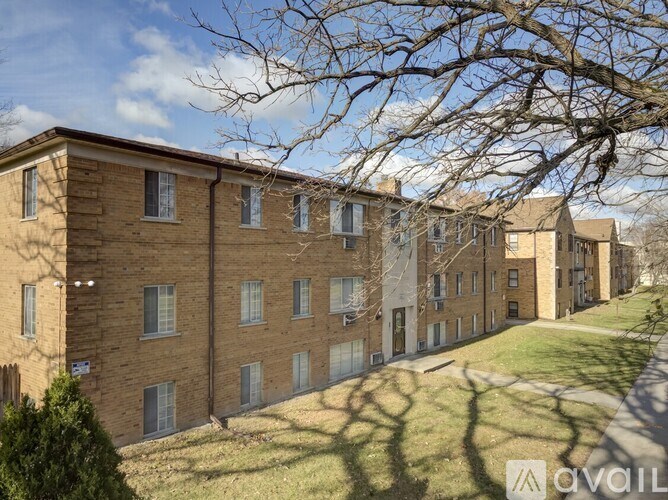 A row of brown brick apartment buildings with trees in front.