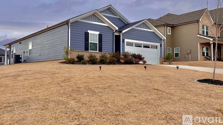 A grassy field with a house and a tree in the background.
