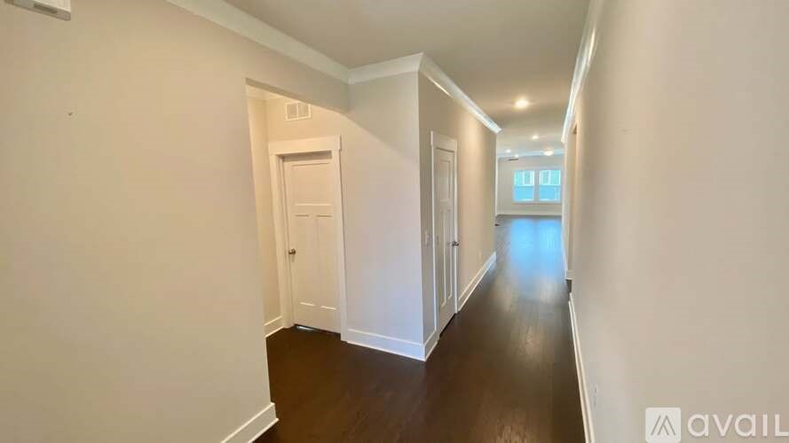 A long hallway with white walls and wood flooring.