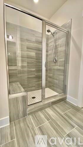 A modern bathroom with a walk-in shower and tiled floor.