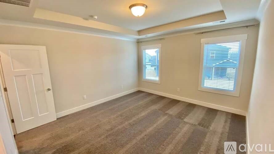 A room with a carpeted floor and a window with blinds.