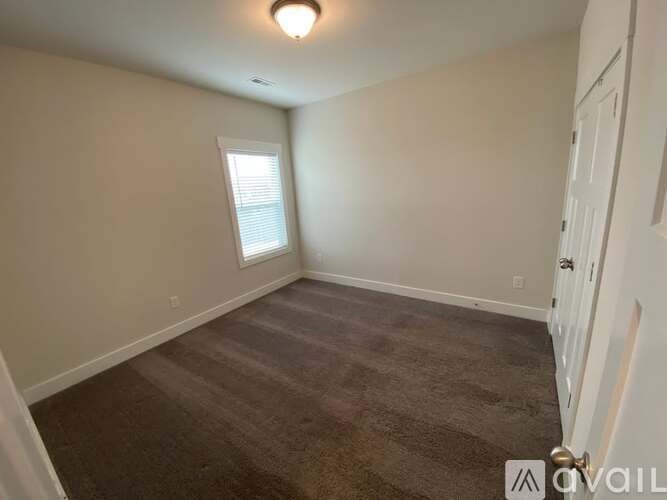 A room with a carpeted floor and a window with blinds.