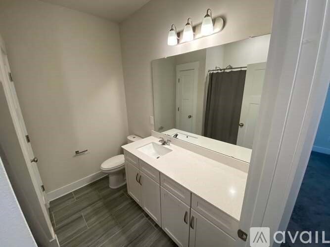 A bathroom with a toilet, sink, and mirror.
