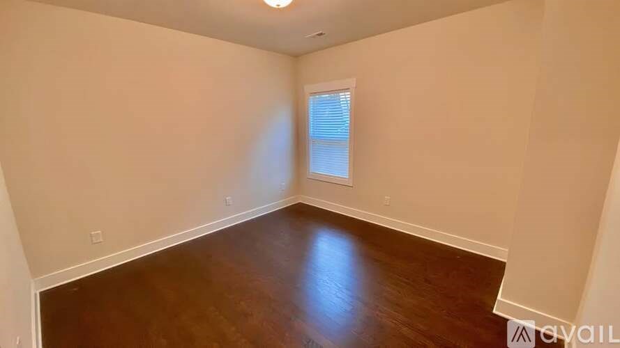 A room with wooden floors and a window with blinds.