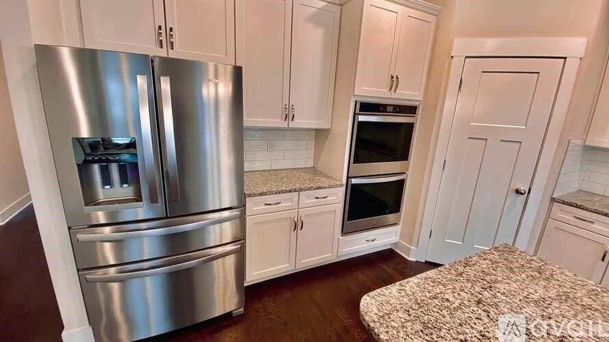 A modern kitchen with a stainless steel refrigerator and white cabinets.