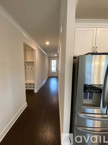 A long hallway with a stainless steel refrigerator on the right.