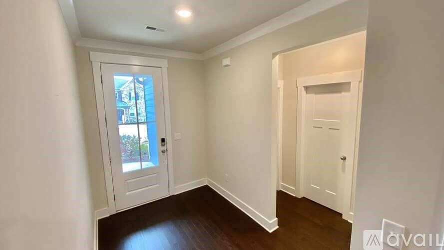 A room with a white door and a window with a view of a building outside.