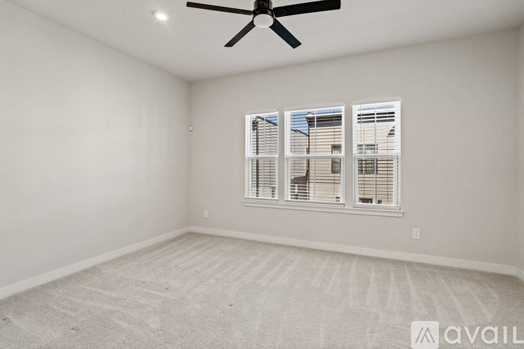 A room with a ceiling fan and a window with blinds.