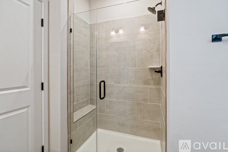 A shower area with a glass door and a white tub.