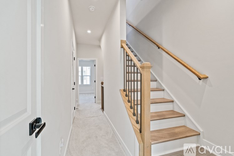 A hallway with a staircase and a door on the left.