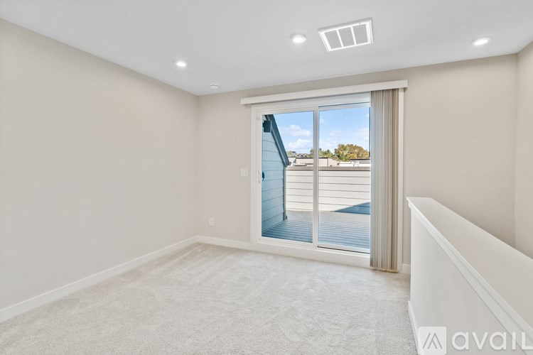 A spacious room with a large window overlooking a deck.