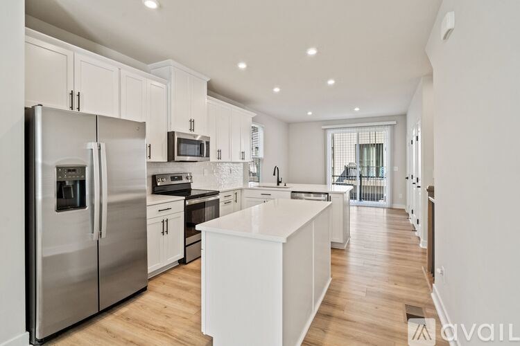 A modern kitchen with a refrigerator, microwave, oven, and sink.