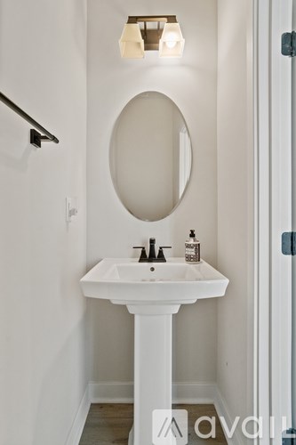 A white sink vanity with a round mirror above it.