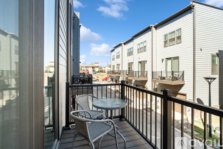 A balcony with a table and chairs overlooks a courtyard.