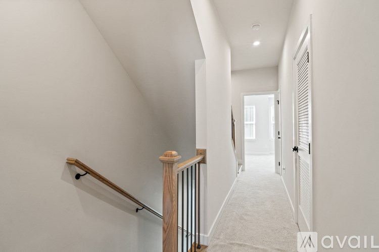 A hallway with a carpeted floor and a wooden staircase.
